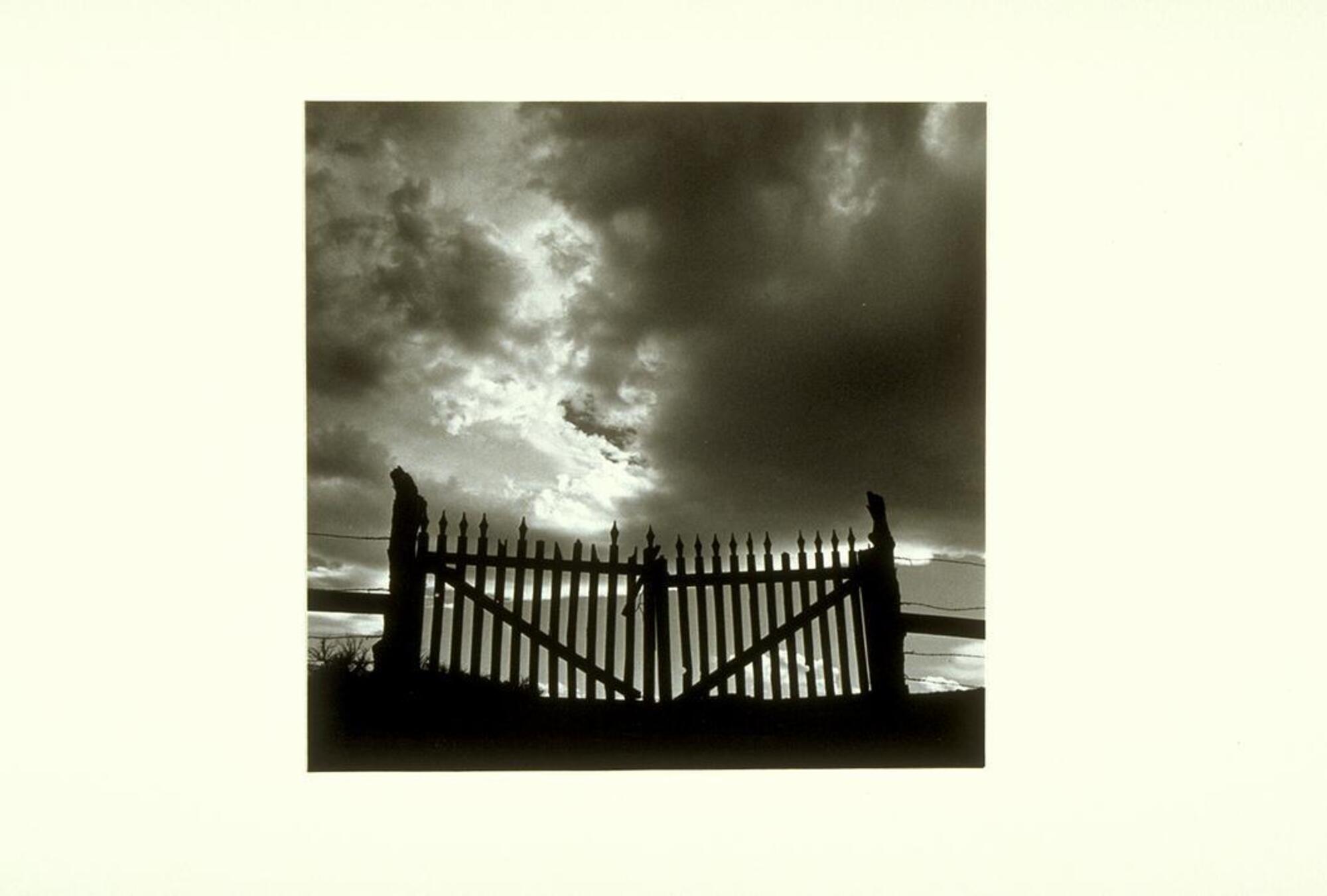 A photograph of a pair of gates set against a cloudy sky.