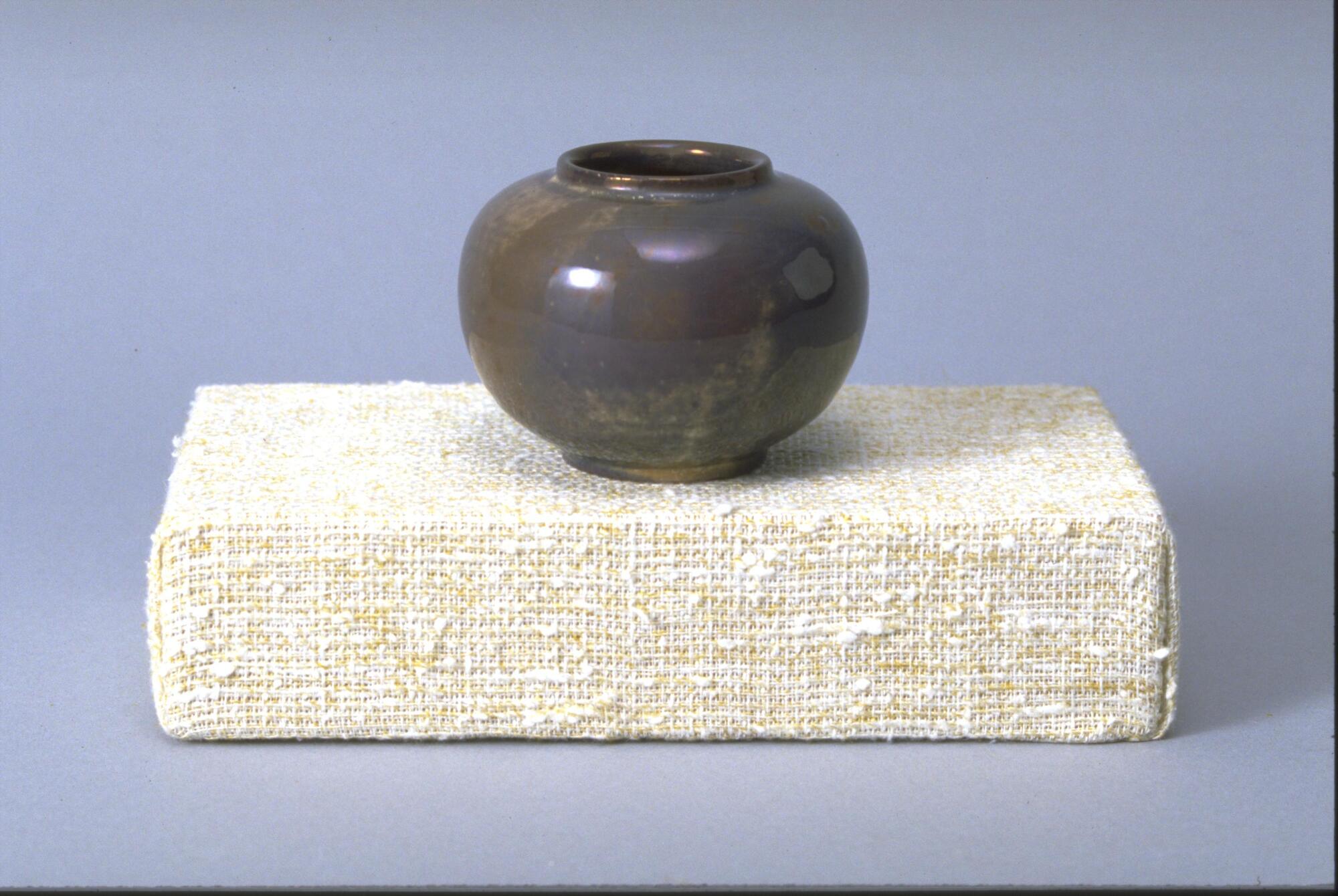 Footed vessel with round body and covered in iridescent muddy gray-ish glaze