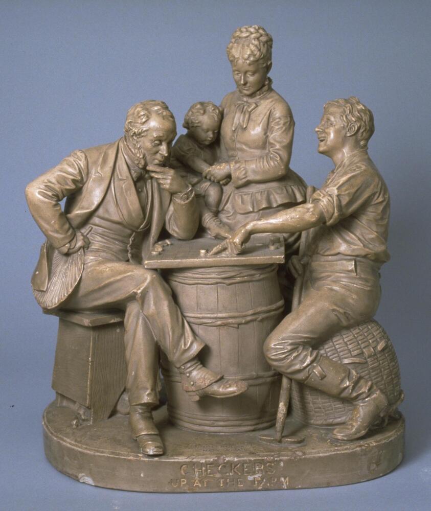 Plaster sculpture depicting two men sitting on stools playing checkers using a barrel as a table with a woman holding a baby standing behind them.