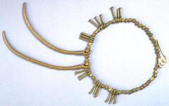 Belt with brass beads and brass pendants. There are six sets of three nail-shaped pendants and two large curved pendants. 