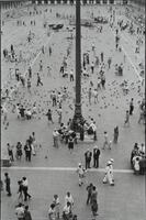 Overhead scene of many people and pigeons in a concrete square.