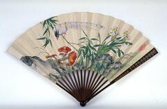 The lower section of the fan has rocks and grasses with mushrooms and several daffodils in bloom. A bird white bird with black face and blue head sits on a thin branch that is coming down from the upper left section of the fan. 