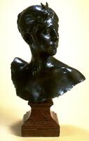Bust-length figure of a woman with head turned proper left, down-turned eyelids and crescent moon atop head; executed in bronze with a rich, dark patina on a brownish stone base.<br />