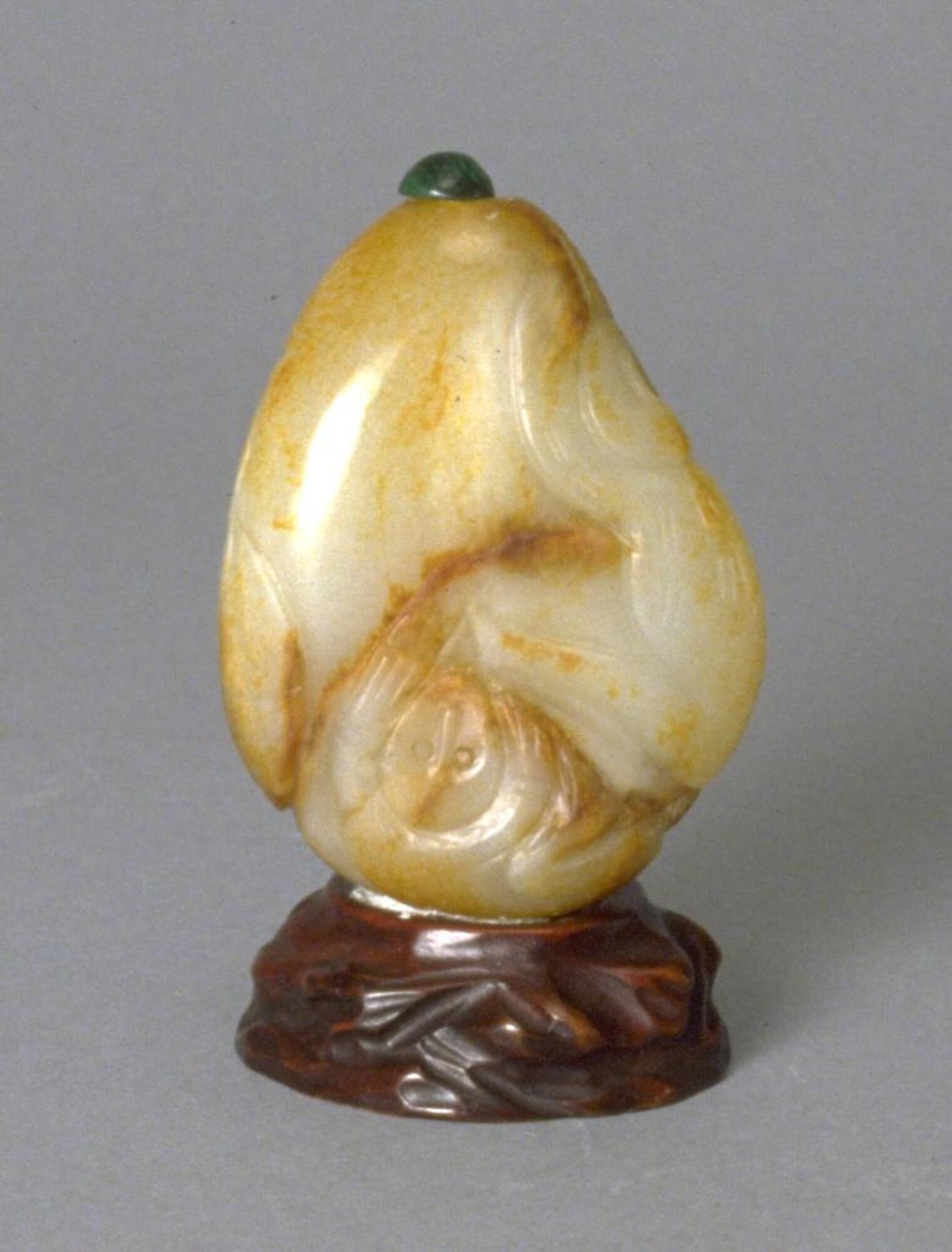 A brown, white, and yellow colored nephrite jade snuff bottle with carvings of a monkey and fish. &nbsp;&nbsp;