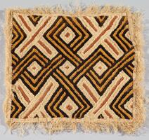 Square panel with cream color fringed edges. The design consists of black and yellow interlocking lines that form a diamond pattern, in addition to intersecting cream bands with burnt sienna colored lines that form X-shaped patterns throughout the panel.
