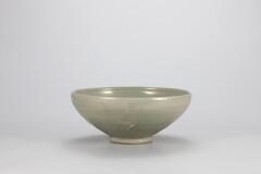 <p>There are many examples of early Goryeo celadon decorated with parrot designs, produced under the influence&nbsp;of Chinese Yue ware. This bowl is decorated with an incised horizontal line on the inner wall just below the mouth and with incised design of a pair of parrots. It has a mouth that curves inwards, and a circle is incised on the inner bottom of the bowl. On its body, there are cracks in two parts, while iron spots are found on the inner wall and the foot. Refractory clay had fallen onto and adhered to the inner bottom, in parts, close to the foot during firing inside the kiln. The glaze was poorly fused overall, however the bowl appears to be high-quality as it had the entire foot glazed and used quartzite spurs to support the vessel during firing.<br />
[<em>Korean Collection, University of Michigan Museum of Art</em> (2014) p.96]</p>
<br />
It has a slightly inverted rim and mildly surved sides tapering gradually to a narrow foot. The graze is dark greenish blue in cloor, leaning toward gree