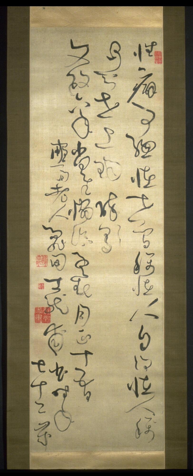 A long hanging scroll with stamps in the top right and middle left of the scroll. The five lines of characters are very shaky.