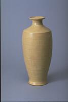 This tall vase has a uniform beige glaze and a slender profile derived from vessels with Asian origin.