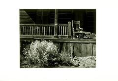 Photograph of a rocking chair on the front porch of a house.