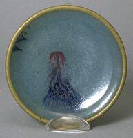 This shallow dish on a footring has opaque sky-blue glaze, thinning to translucency at the rim with copper purple splashes to the interior.