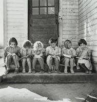 A group of little girls sitting on the stairs in front of a school.