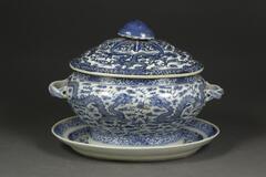 Porcelain blue and white covered soup tureen with platter depicting dragons and clouds.
