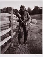Army Reinactment. Army colonel stainding next to a fence in a field. Has a large knife strapped across his chest.