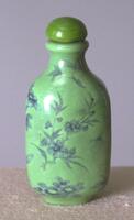 A green snuff bottle with blue floral designs. On the top is a green glass stopper.