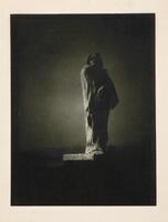 This photogravure is one of a series of photographs commissioned by Auguste Rodin of his statue of the French writer Honoré de Balzac. The cloaked figure is off-center and facing to the right of the frame. The sculpture emerges from the landscape, illuminated by light from behind and to the left.