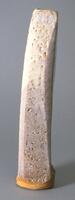 It is a vertically long, rectangular shaped vase. The body is slightly tilted; its four corners are shaved from the top to the bottom. The clay color is orange-yellow; the body is glazed with porous, milky white ash glaze. The bottom edge of the body and the bottom are unglazed. It has no foot.