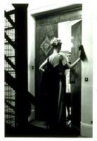 This photograph depicts two women facing each other in the door way of an upper class apartment.