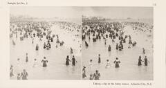 This black and white stereoscopic image features two images of a view of people wading in the surf at a beach. It is surrounded by the text: Sample Set No. 1; Taking a dip in the briny waves.  Atlantic City, N.J.<br />