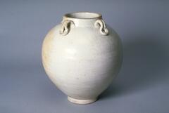 A large globular jar on a narrow footring, with a wide, short mouth and a direct rim, and four louped coil lugs attaching the neck to the shoulder, covered in a white glaze.