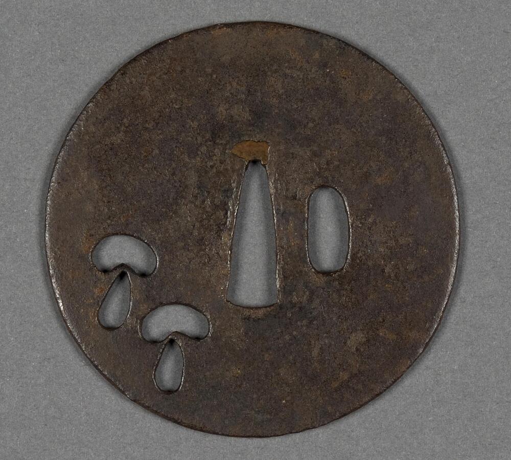 Circular tsuba, made of iron. It has two holes in the middle. There are two openwork motifs of mushrooms on the lower left. Rusts on some parts of the piece.
