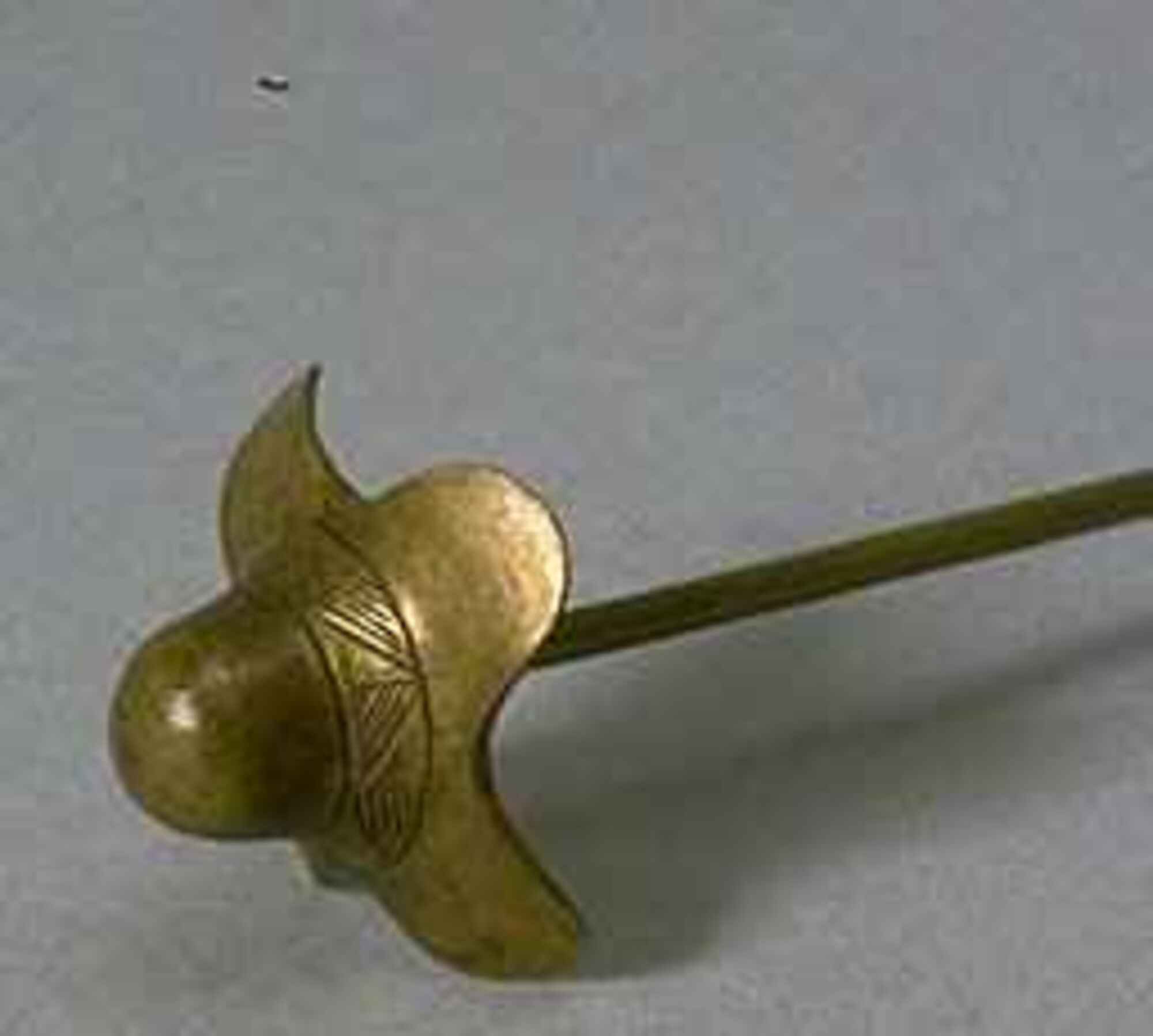 Pin with designed bulb-like pinhead. Head of the pin is round with its base flowering into four round petal-like shapes. Wrapping around the middle portion of the pinhead is a geometric pattern. 