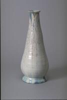 Teardrop-shaped ceramic vessel with foot, long tapering neck and flared lip covered with a mottled white matt glaze