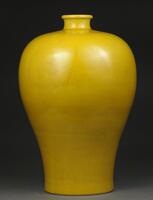 This yellow Meiping vase has a thin base that widens towards the top and is followed by a round shoulder, a narrow neck, and small opening that slightly flares out. Carved one the surface of the vase are patterns of clouds and dragons.