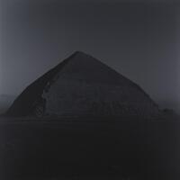 Dark image of a pyramid at night.