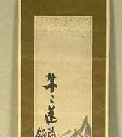 Long, thin hanging scroll with a black/grey ink painting on a gold cloth backing. Writing is in the upper left side of the painting. The painting itself depicts stalks of bamboo.