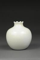 Blanc de chine vase with pomegranate shape. It has a round bulbous body that narrows at the neck and has a pointed rim like the top of a pomegranate.