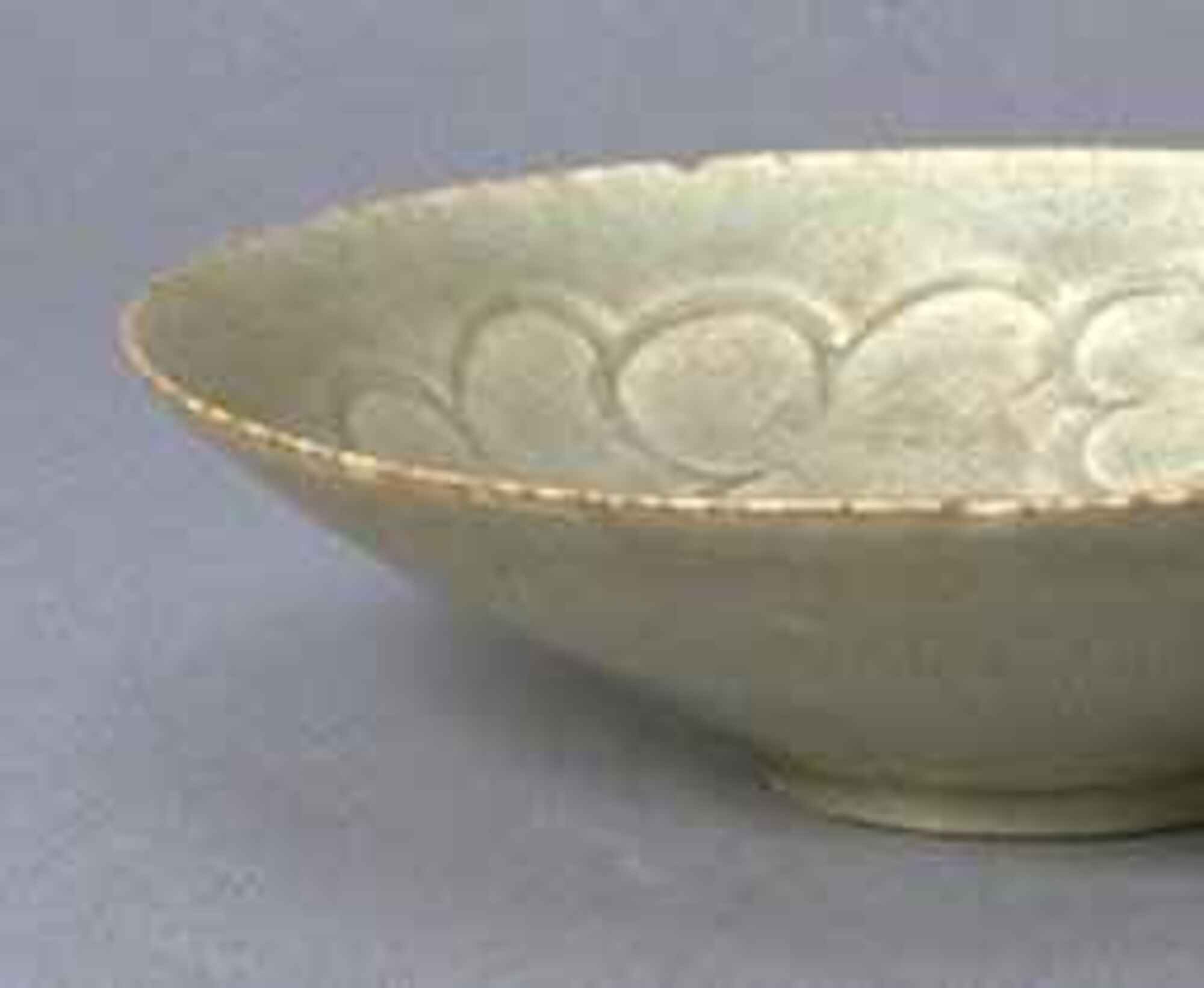 Thin porcelain conical bowl with direct rim on a footring. The interior has a molded, incised cloud decoration, and is covered in a white glaze with bluish tinge.