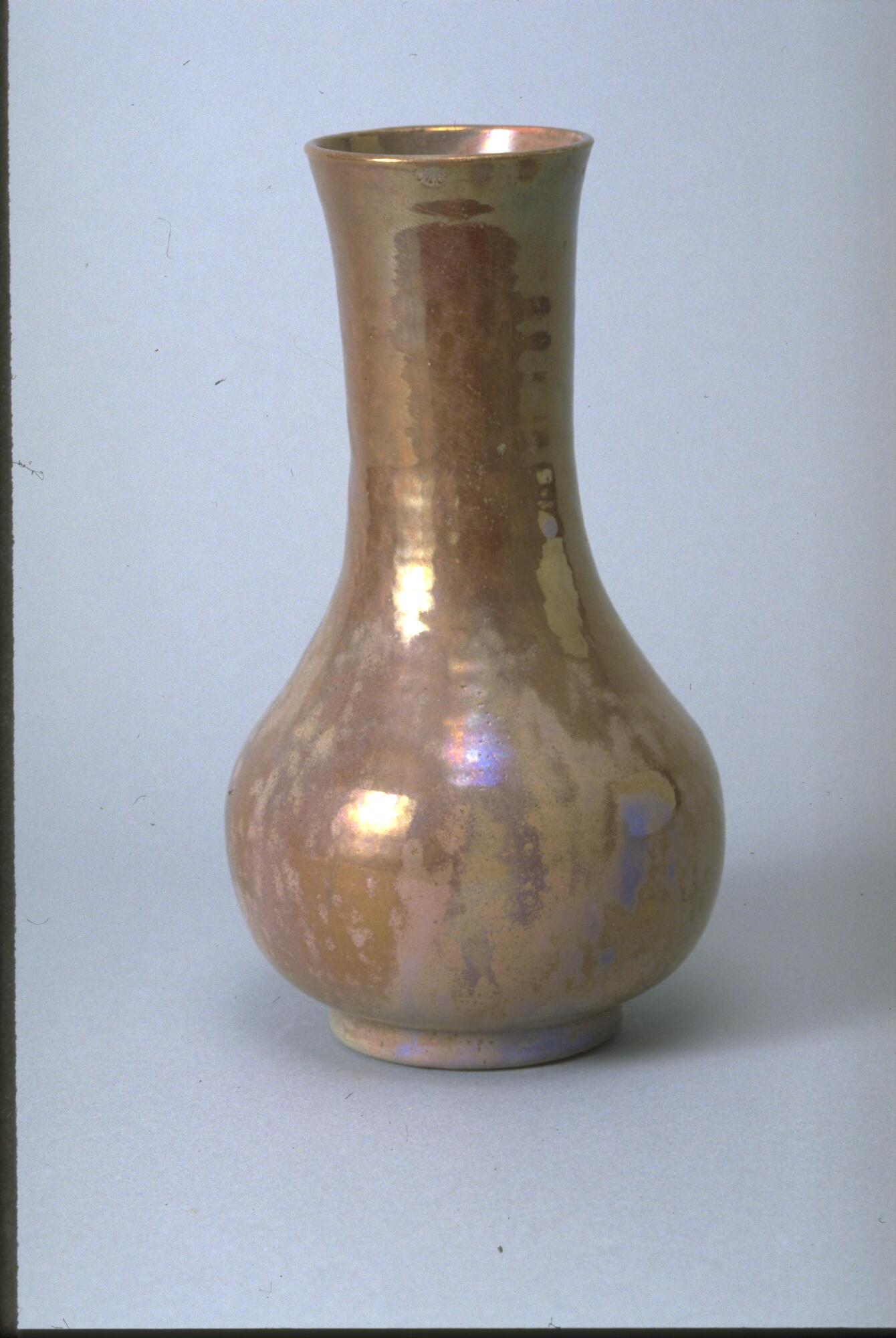 Bottle-shaped vessel with foot, bulbous body and long neck covered in an iridescent light brown-ish glaze