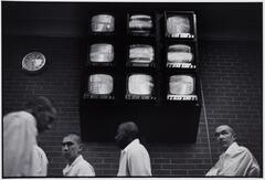A group of prisoners standing with nine television screens above their heads.