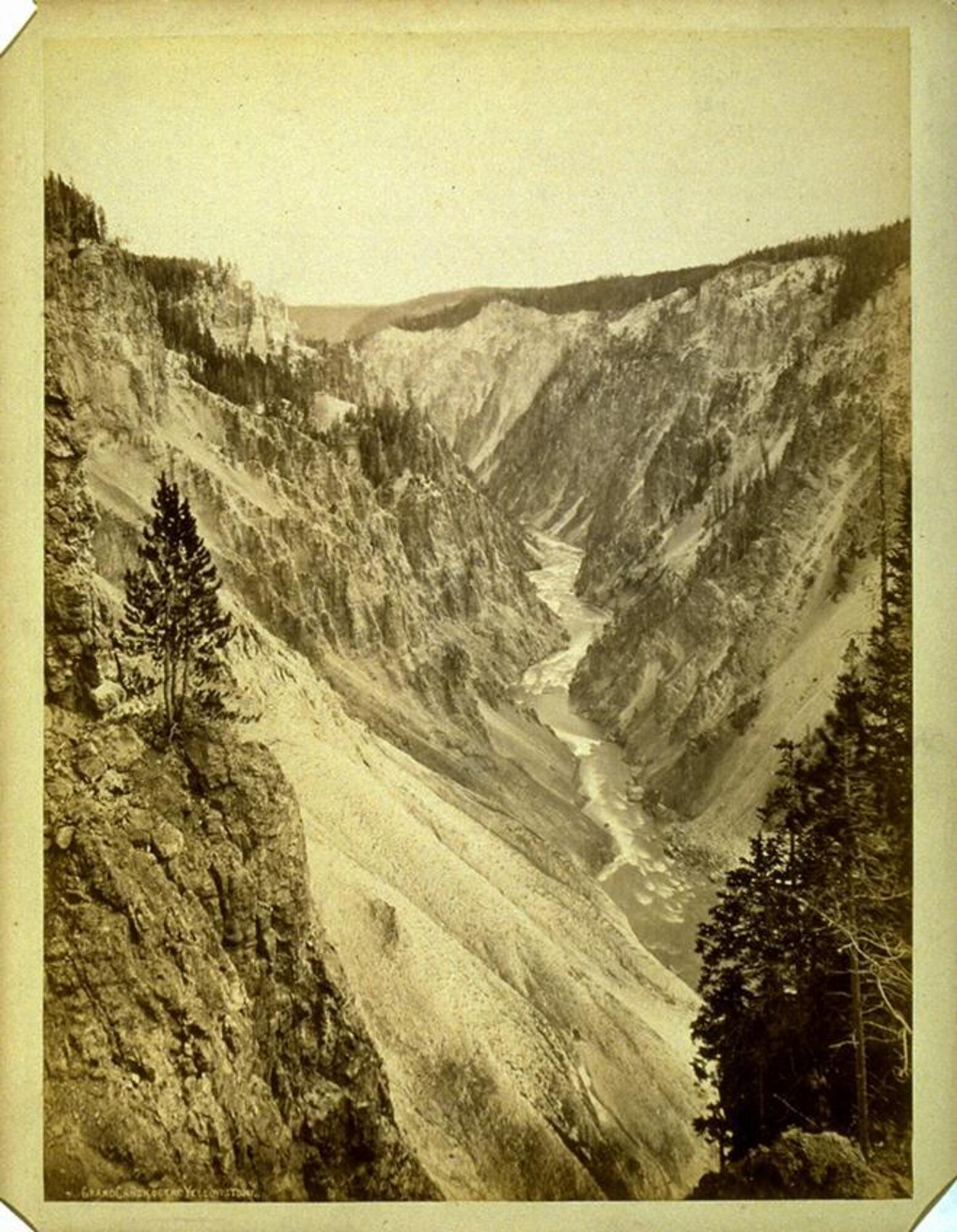Photographed from a high vantage point, this image depicts a vertical view looking down into a rugged canyon with a river running along its bottom.
