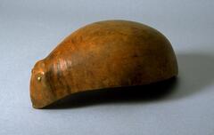 Wooden, approximately oval-shaped bowl with inset brass eyes on one end, making it look like an animal. 