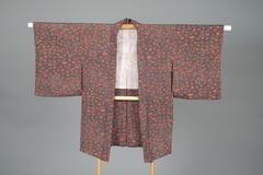<p>Orange patterned (komon) chirimen haori with dyed brown, white, and yellow-orange dotted chrysanthemum motif patterning with an off-white lining with light gray crane and pine motifs</p>
