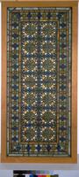 Window in geometric patterns of white, blue, and amber colored glass set in a modern wooden frame.