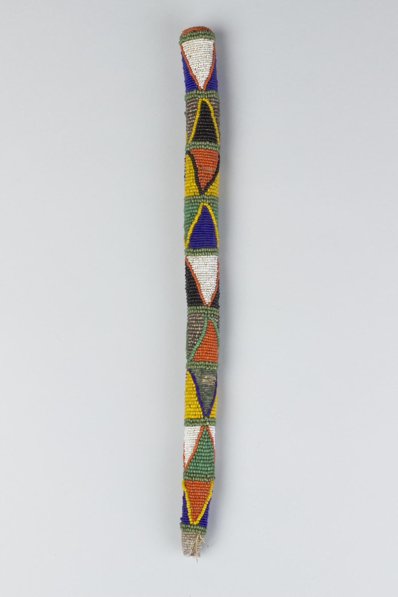 Wooden staff covered with multi-colored beadwork in repeating triangular patterns. 
