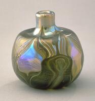 This small bottle consists of iridescent glass with both a mirror-like quality and swirling leaf-like design the extends from the bottom of the vessel to the neck.
