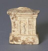 A small, thin, earthenware molded plaque with a bas-relief architectural scene of a Chinese three-bay building on a dais. There are two slat windows and a hipped roof. A figure stands in the central doorway. The plaque is covered in a white slip.
