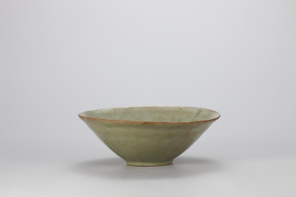 <p>The bowl has a low, narrow foot, and diagonally aring out sides. It is decorated with raised designs on the inner wall, but they are so low relief that it is di cult to recognize what they are. The outer base retains three quartzite spur marks. Damage to a side of the mouth rim and the center of the bowl has been repaired.<br />
[<em>Korean Collection, University of Michigan Museum of Art </em>(2014) p.99]</p>
It flares out widely at the rim, then back in. Its sides, otherwise almost straight, taper to the base. There is no decorated.