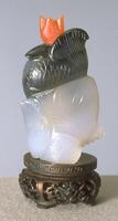 An agate snuff bottle carved in the shape of half of two fish. On the top is a glass stopper.