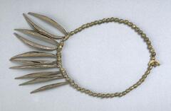 Apron in the form of a belt of brass beads with ten curved pendants. 