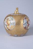 A gold colored porcelain urn. Images are included on the sides.