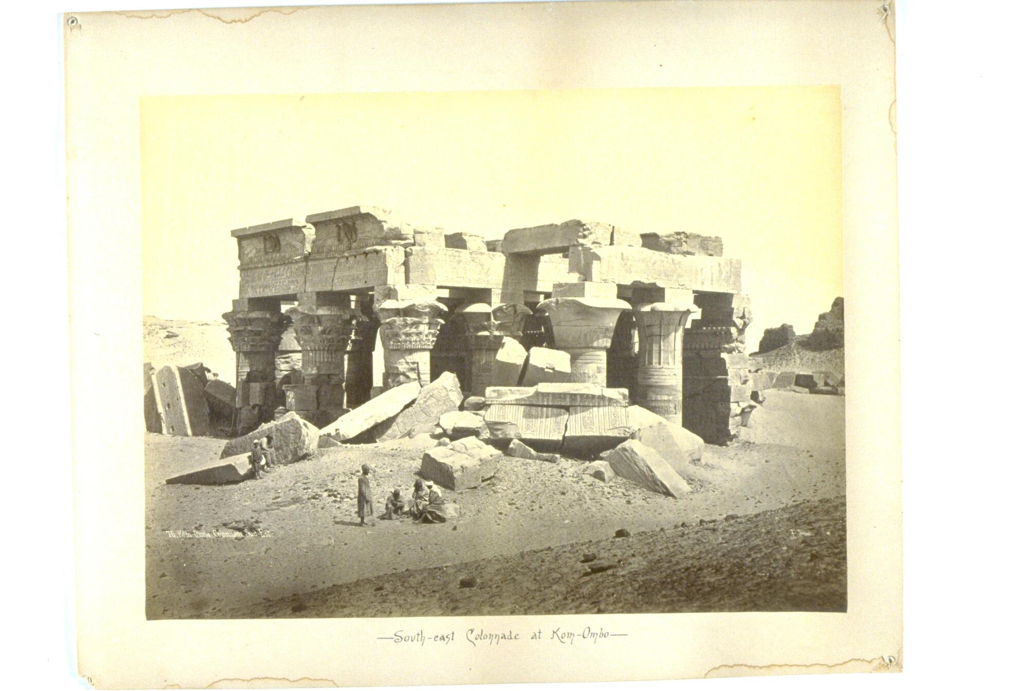 A group of columns stands amid a pile of stone debris in the desert. 