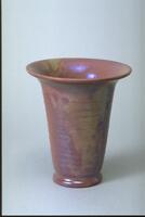 Cylindrical ceramic vessel with large flared rim covered in iridescent glaze over a semi-matte glaze that creates an appearance of irregular patches of color with an overall dark rose appearance.