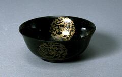 Deep green jade bowl with gold dragon medallion decoration on both the inside and outside of the bowl.