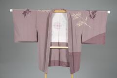 <p>lavender silk haori with dyed white and violet bamboo leaves with gold embroidery on the left front sleeve, back right sleeve, with one family crest (kamon) on the backside with a white silk inner lining with Karahana (stylized Chinese flower) motifs.&nbsp; The left side and left sleeve purposely contain darker lavender to emphasize asymmetry.</p>
