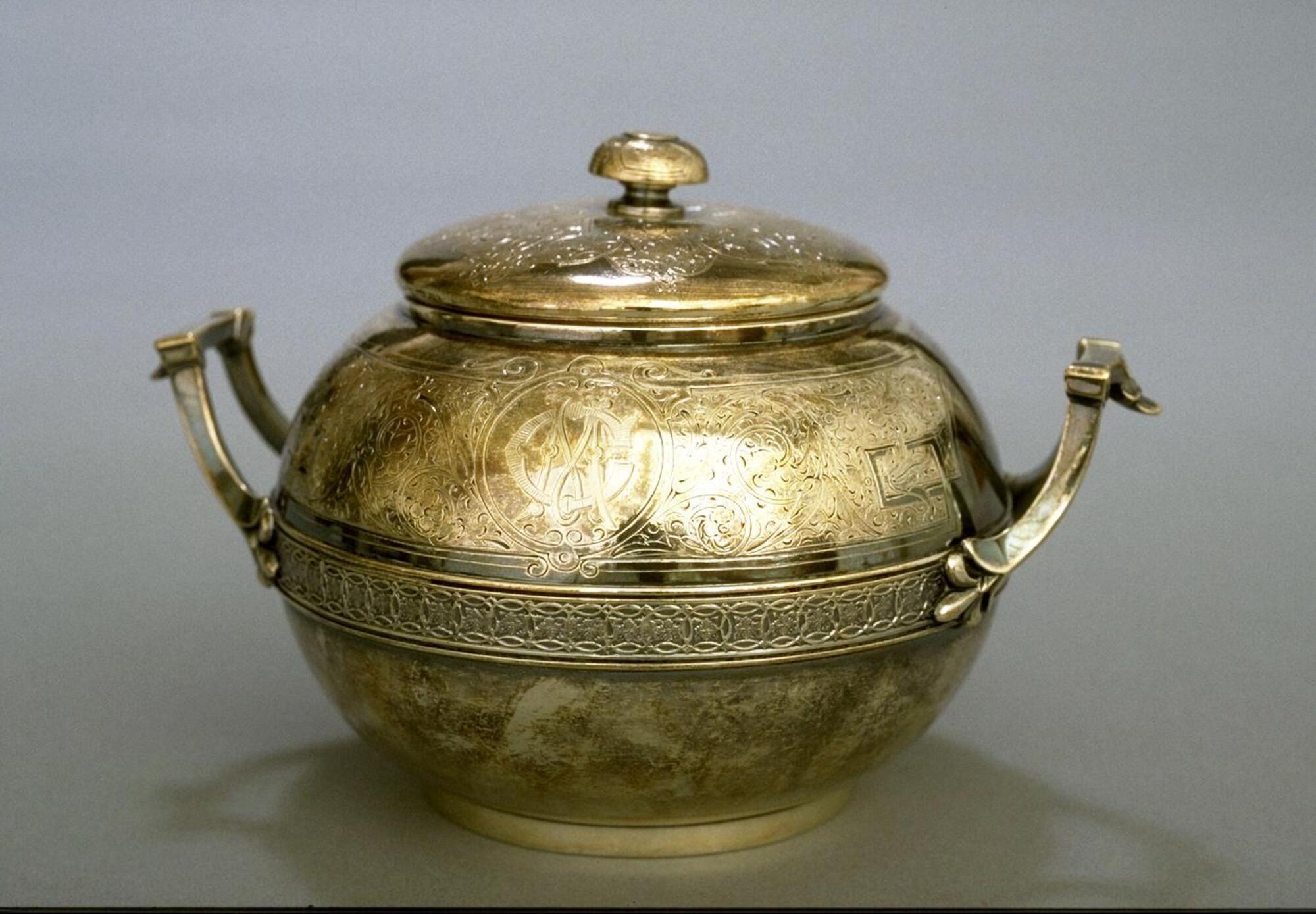 Two-handled jar-shaped silver vessel with lid and a band of decoration around center of the body