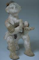 Clay female figure seated on a stool, holding a nursing baby. 